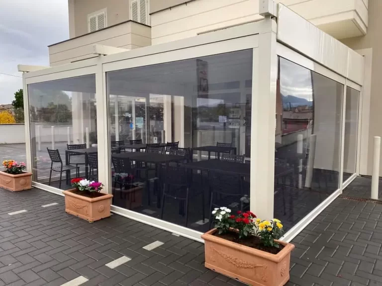 Vetrotenda che chiude una pergola davanti a un locale