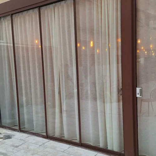 Esempio di un locale con spazio esterno chiuso da vetrate panoramiche e tende da interno
