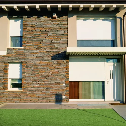 Casa in mattoni con due finestre e due grandi vetrate protette da una schermatura zip