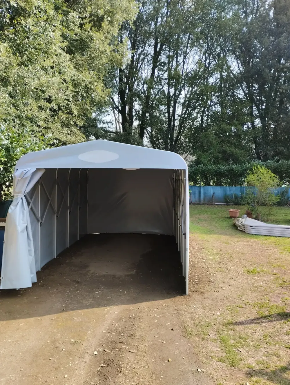 Box auto con telo in pvc grigio posizionato sullo spazio esterno di una abitazione