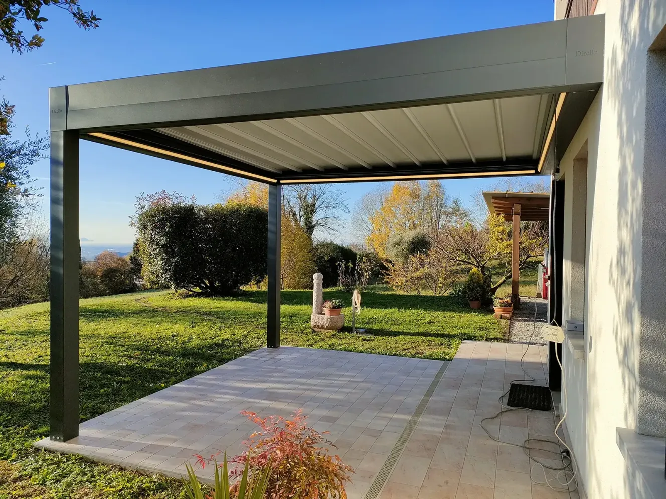Tecnozen Pergotenda impacchettabile piana A1 su spazio esterno con giardino