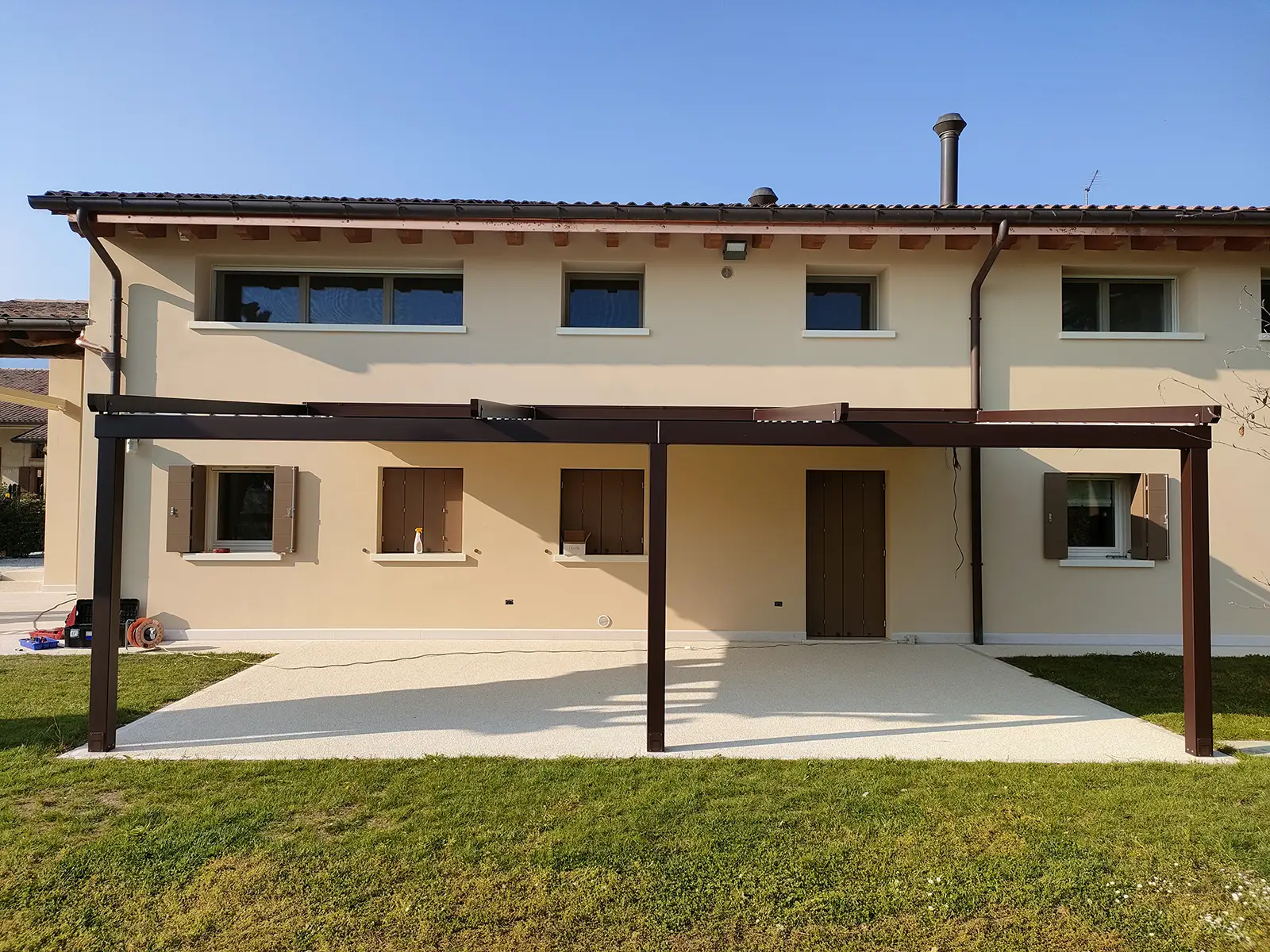 Spazio esterno con giardino e la pergotenda impacchettabile inclinata K1 personalizzata