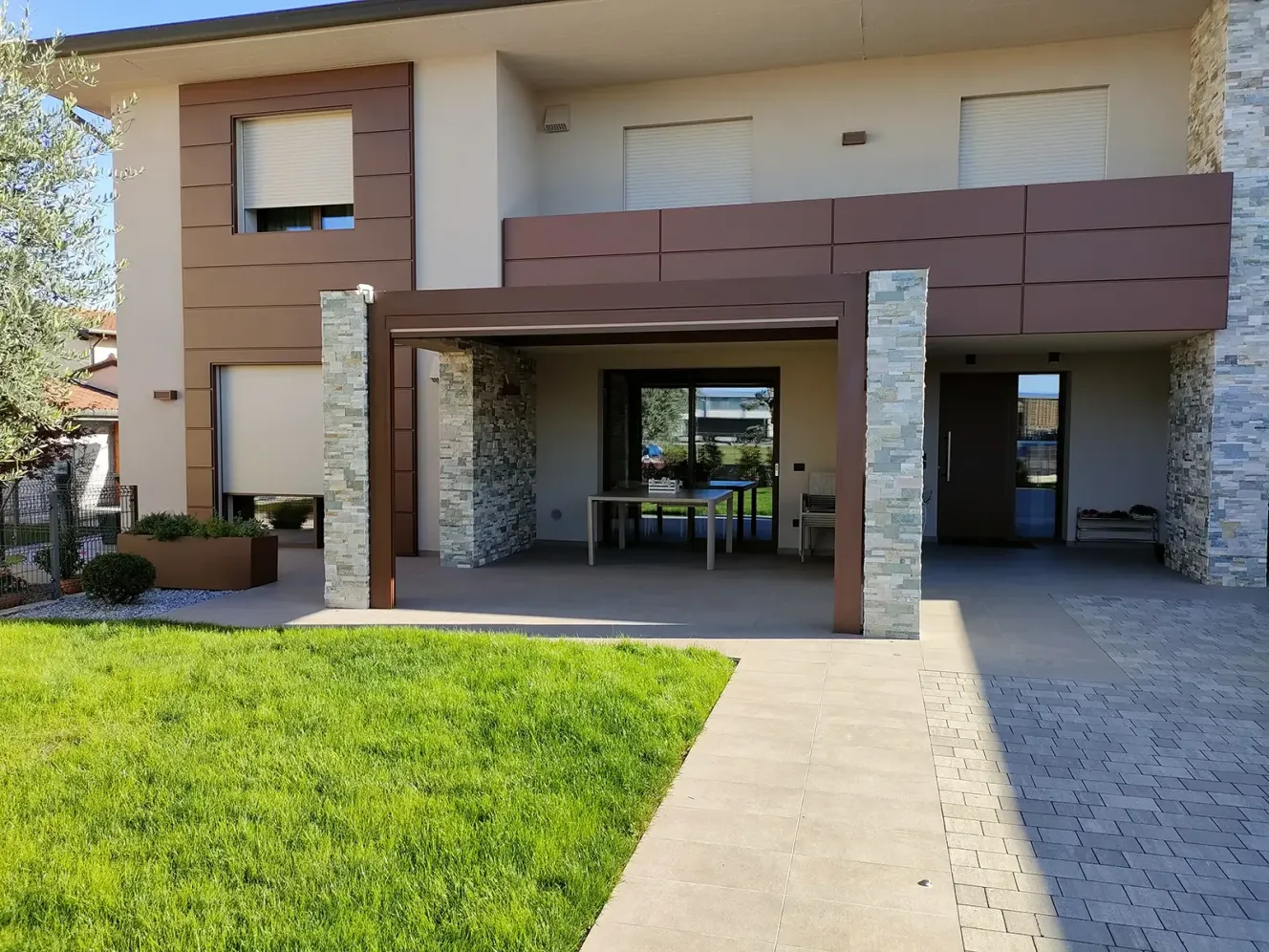 Pergola bioclimatica orientabile 4.5 in corten su esterno di un casa moderna con pilastri in mattoni